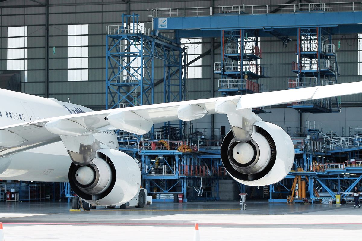 Un avion de ligne en maintenance dans un hangar, entouré de passerelles d'accès.