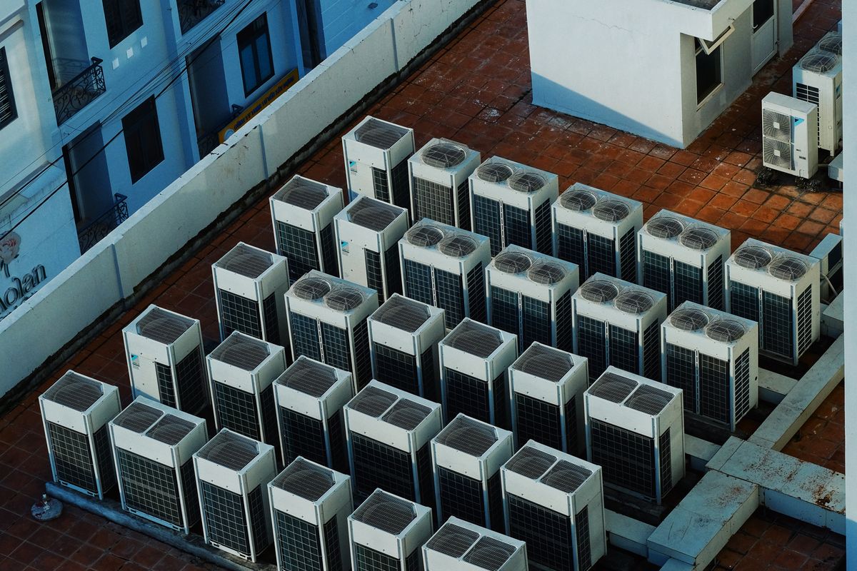 Vue plongeante sur les groupes extérieurs de climatisation en toiture d'un immeuble.